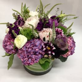 Mixed purple and white flowers arranged in a glass vase