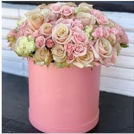Pink and cream roses arranged in a round pink box