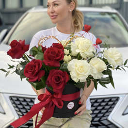 Red and white roses in a black hatbox with a red ribbon