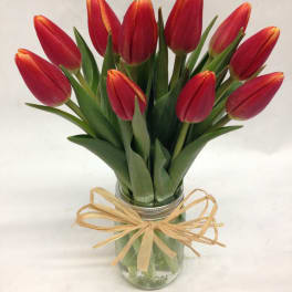 Red tulips in a glass jar tied with a raffia bow