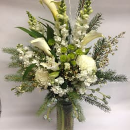 Tall white floral arrangement in a glass vase with calla lilies and snapdragons