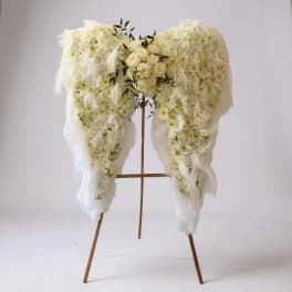 White floral funeral spray on a wooden stand