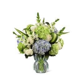 White roses and blue hydrangeas in a clear glass vase