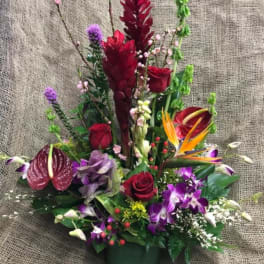 Mixed tropical bouquet with red roses and purple orchids in a dark vase