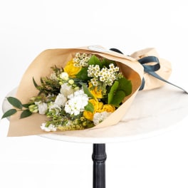 Bouquet of yellow and white flowers wrapped in kraft paper