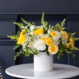 Yellow and white roses arranged in a white vase