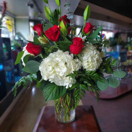 Red roses and white hydrangeas in a clear glass vase