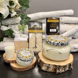 Candles and fragrance products arranged on wood slices with faux flowers