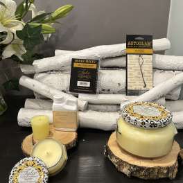 Candles and fragrance products arranged with a white lily bouquet