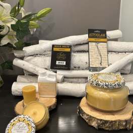 White lilies beside yellow candles and fragrance products on wood slices