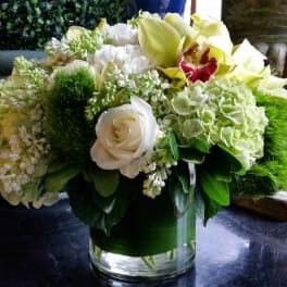 White and green floral arrangement in a clear glass vase