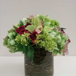 Mixed green and burgundy flowers arranged in a glass vase