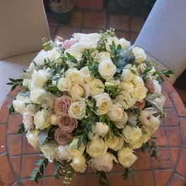 Large bouquet of white and blush roses with greenery on a chair