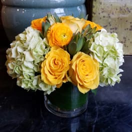 Yellow roses and white hydrangeas arranged in a glass vase