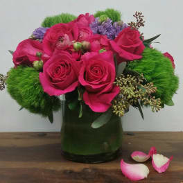 Pink roses and purple flowers in a green glass vase with bright green accents