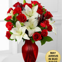 Red roses and white lilies arranged in a red glass vase