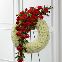 Red and white floral funeral wreath on a stand
