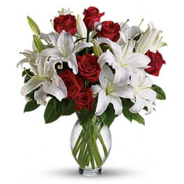 Red roses and white lilies arranged in a clear glass vase