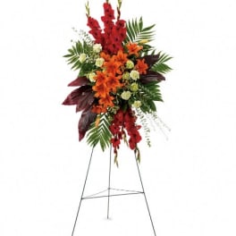 Tall floral standing spray with red and orange flowers on a metal easel