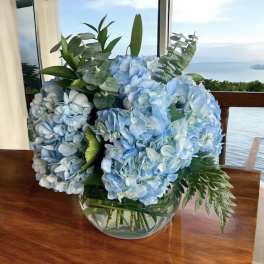 Blue hydrangea arrangement in a clear glass bowl vase