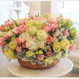 Large pastel flower arrangement in a low round bowl