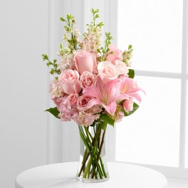 Pink roses and lilies arranged in a clear glass vase