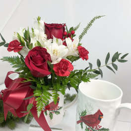 Red roses and white flowers in a mug with a ribbon bow
