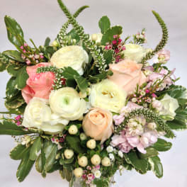 Mixed bouquet of pale roses and white blooms in a glass vase