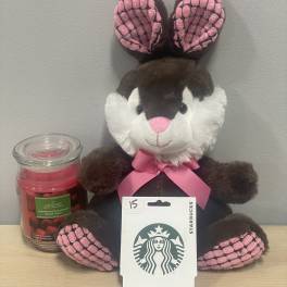 Plush bunny with a pink ribbon beside a candle and Starbucks gift card