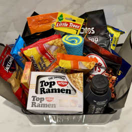 Gift basket filled with snack bags, ramen, and a drink bottle