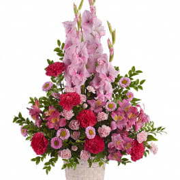 Pink and red mixed flower arrangement in a woven basket
