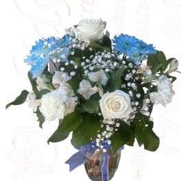 White and blue flower bouquet in a glass vase with ribbon