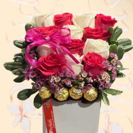 Pink and white roses in a square box with a ribbon and chocolates