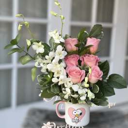Pink roses and white orchids in a Snoopy mug vase