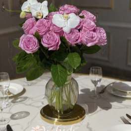 Pink roses and white orchids in a glass vase on a table