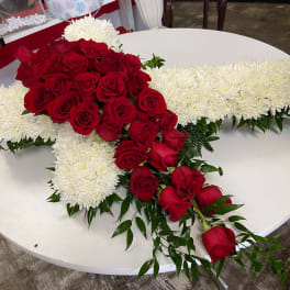 Red roses arranged over a white cross-shaped floral tribute