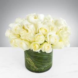 Bouquet of white roses in a glass vase with green stems visible