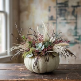 Pumpkin-shaped container with a dried floral arrangement in muted tones