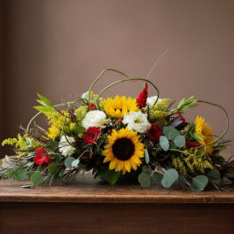 Low floral arrangement with sunflowers, white blooms, and red accents