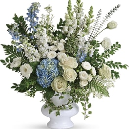 White and blue floral arrangement in a white pedestal vase