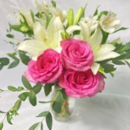 Pink roses and white lilies in a clear glass vase