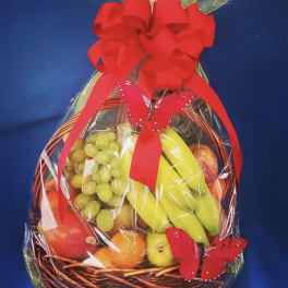 Fruit basket wrapped in clear cellophane with a red bow