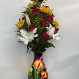 Tall bouquet of red roses, white lilies, and yellow sunflowers in a painted vase