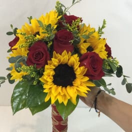 Bouquet of red roses and yellow sunflowers with greenery