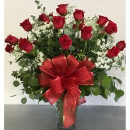Red roses in a clear vase with a large red bow