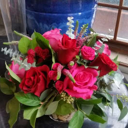 Bouquet of red and pink roses with greenery in a low vase