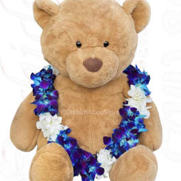 Plush teddy bear wearing a blue, purple, and white flower lei