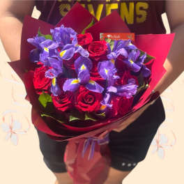 Bouquet of red roses and purple irises wrapped in burgundy paper