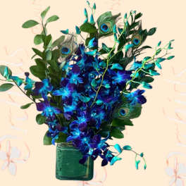 Blue orchids and peacock feathers in a green glass vase
