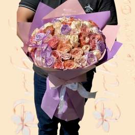 Large bouquet of pastel roses wrapped in purple and pink paper